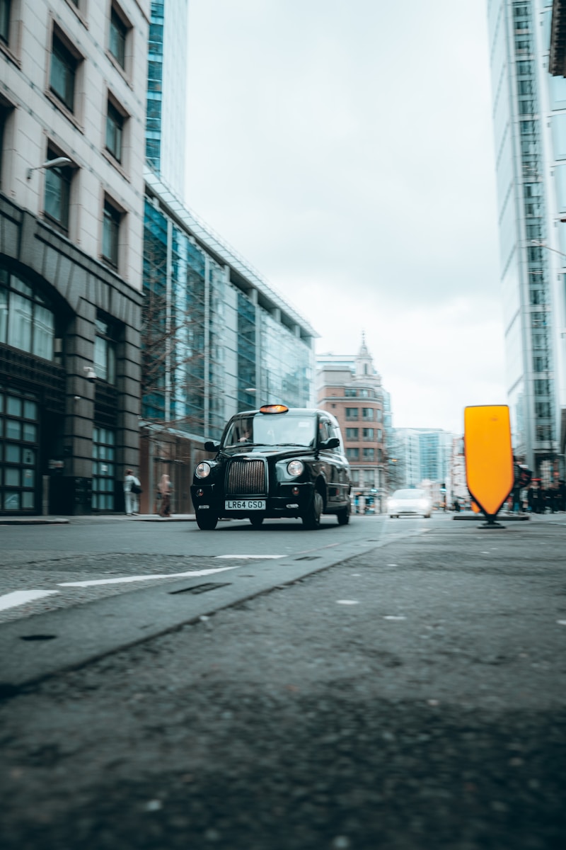 A black london taxi drives down a city street.